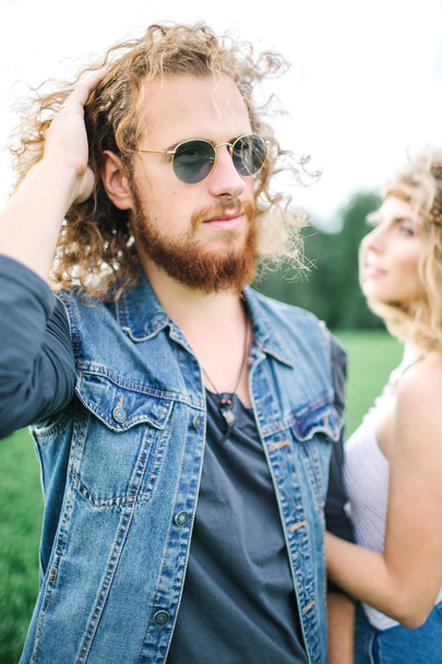 Young hippie male with beard hugging curly female outdoors - Фото, изображение