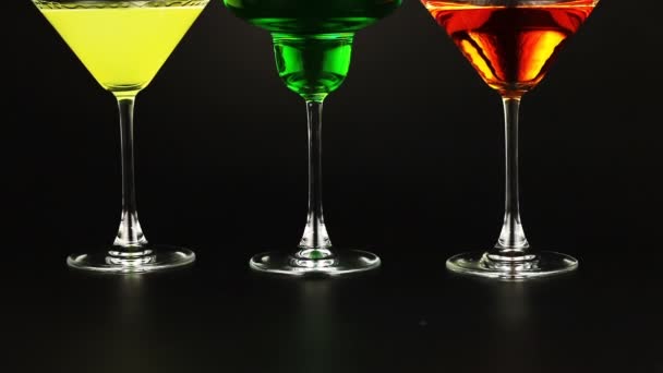 Yellow, green and orange cocktail into glasses on pink background - Footage, Video