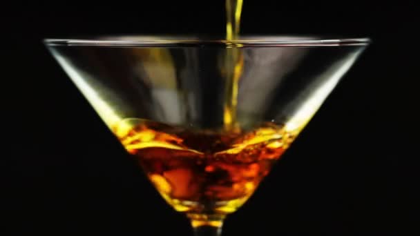 Verser un cocktail orange en verre de martini sur fond noir
 - Séquence, vidéo