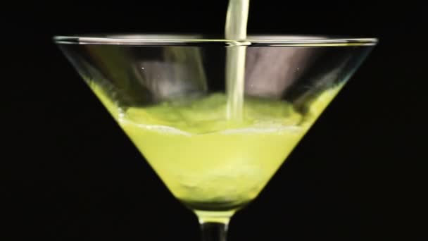 Napływać żółty koktajl martini szkła na czarnym tle - Materiał filmowy, wideo