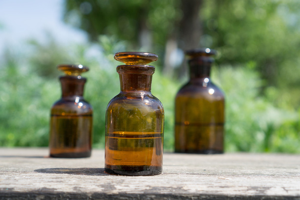 little brown bottles on wooden board and green grass - 写真・画像