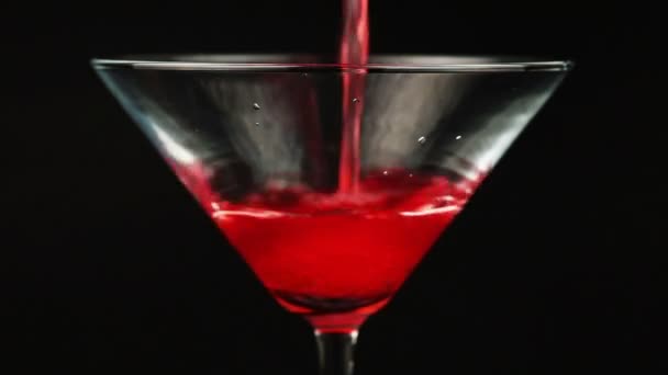 Gieten van rode cocktail in Martiniglas op zwarte achtergrond - Video