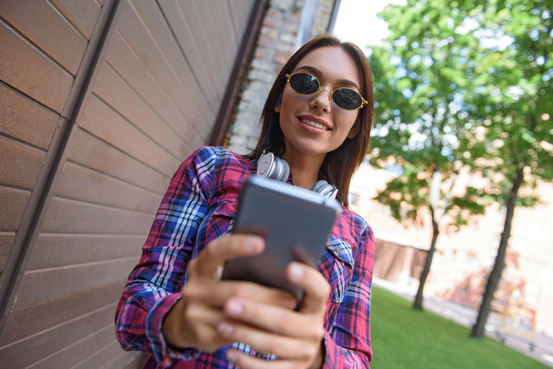 Joyful girl using smartphone outdoors - Foto, immagini