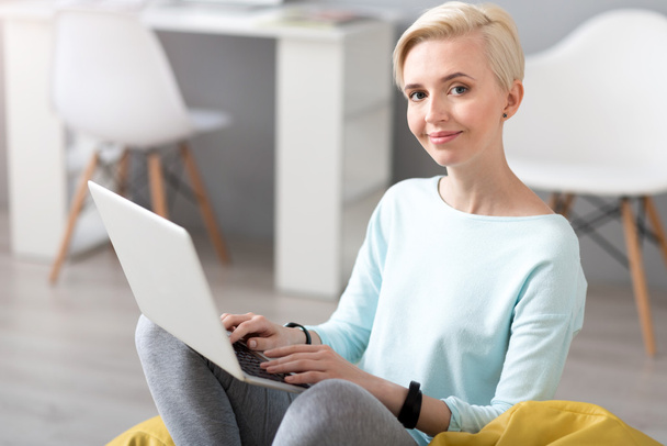 Woman looking at camera and using laptop - Foto, Imagen
