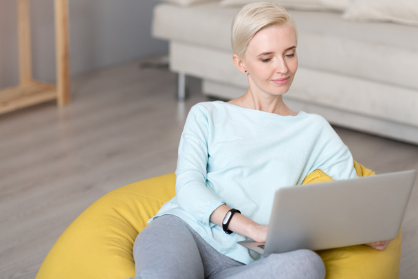 Relaxed woman using laptop while sitting - Photo, Image