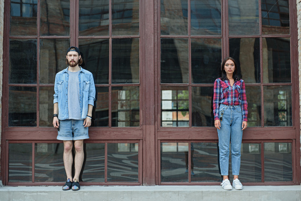 Serious hipster couple stands near building - 写真・画像