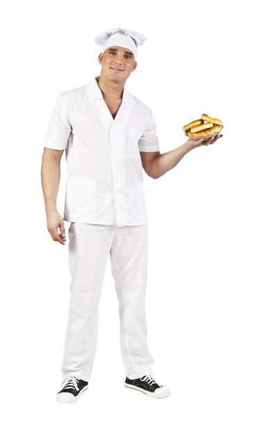 Attractive man in white uniform  carrying a bowl of freshly baked cookies isolated on white - Фото, изображение