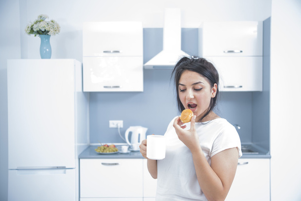 Mujer joven comiendo pastel en la cocina
  - Foto, imagen