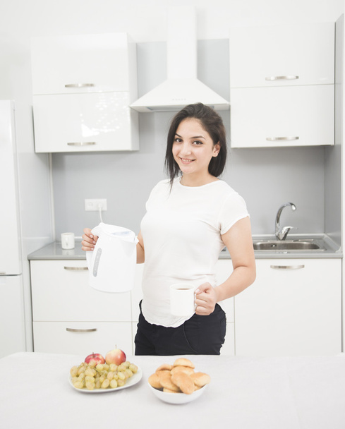 Young woman holding kettle and cup - Φωτογραφία, εικόνα