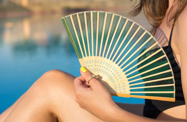 Chica en bikini sosteniendo un ventilador de mano junto a la piscina
 - Foto, Imagen