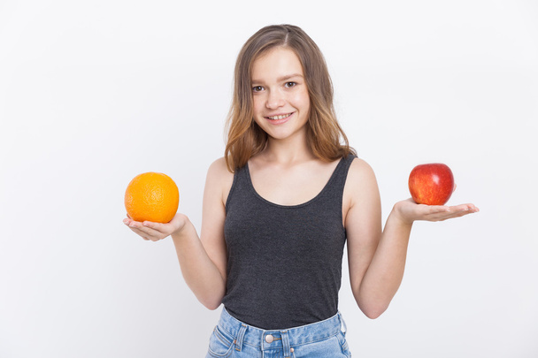 Girl in jeans holding orange and apple - Fotoğraf, Görsel