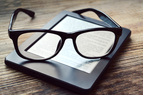 schwarzer Lesegerät mit Retro-Brille auf Holztisch - Foto, Bild