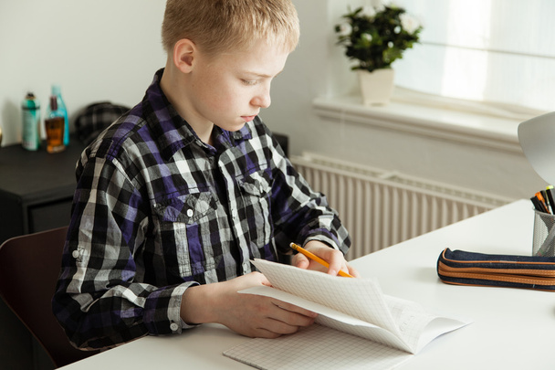 Mladí dospívající chlapec sedí u stolu, dělat domácí úkoly - Fotografie, Obrázek