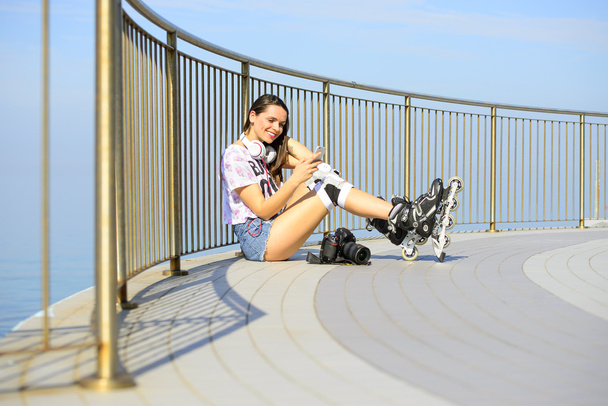 menina bonita em shorts jeans curtos, sentado na praia com uma câmera profissional e sorrindo
 - Foto, Imagem