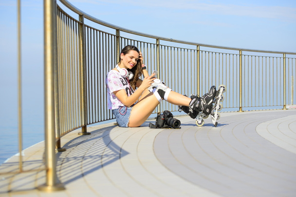menina bonita em shorts jeans curtos, sentado na praia com uma câmera profissional e sorrindo
 - Foto, Imagem