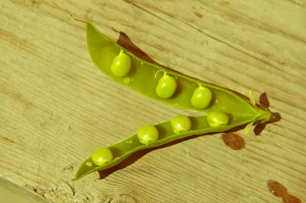 Відкриті зелені горохові горіхи з горохом у старому дерев'яному столі
 - Фото, зображення