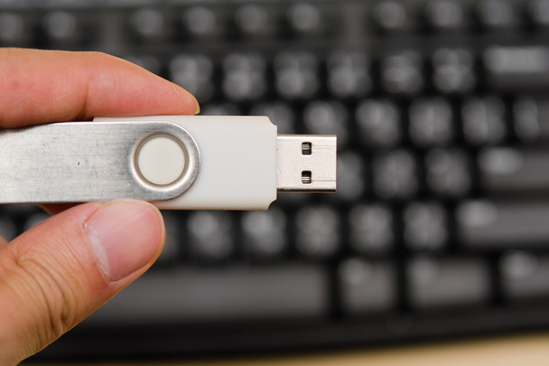 Κίνηση αντίχειρων USB με το χέρι που κρατά σε φόντο πληκτρολόγιο - Φωτογραφία, εικόνα