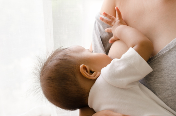 Borstvoeding moeder haar pasgeboren baby naast venster - Foto, afbeelding
