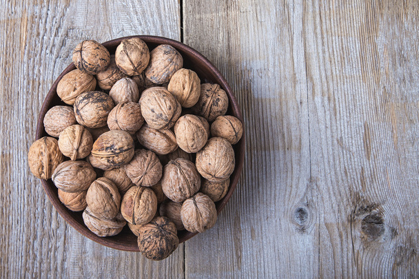 walnuts in a clay plate on a wooden background. top view - Fotoğraf, Görsel