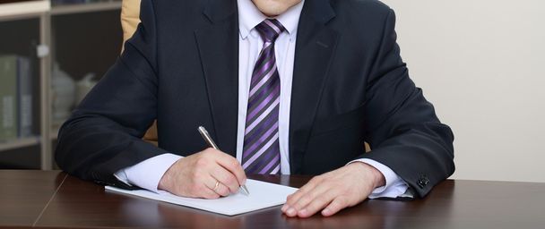 Empresário sentado na mesa do escritório e assinando um contrato
 - Foto, Imagem