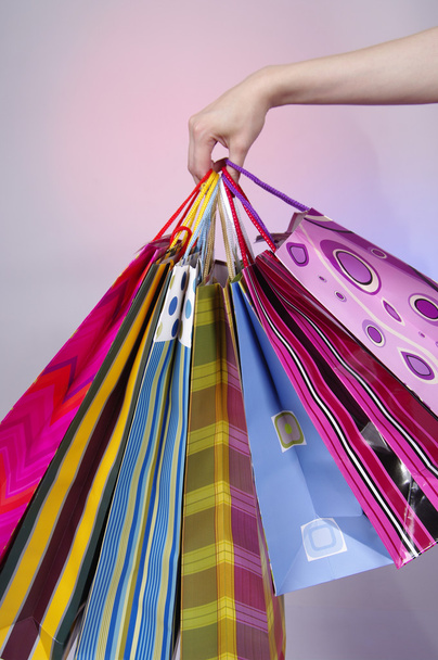 Female hand holding colorful shopping bags - Фото, изображение