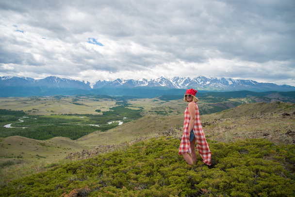 Frau steht im Gras und blickt in die Berge - Foto, Bild