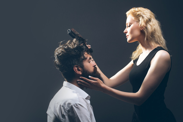 blonde hairdresser combing bearded man - 写真・画像