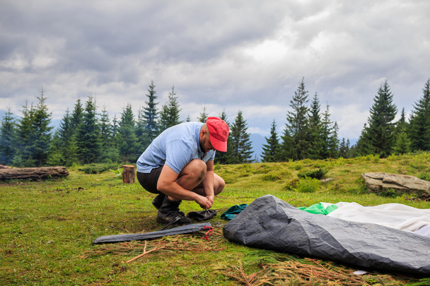 Человек разбивает палатку в кемпинге, горы, концепция путешествия
 - Фото, изображение
