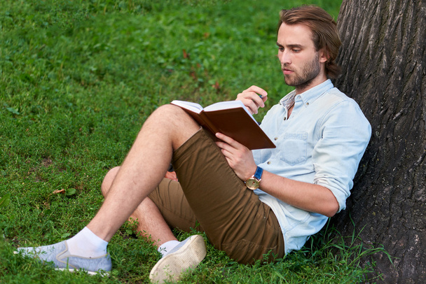 Serious student in park of campus read a book - Φωτογραφία, εικόνα