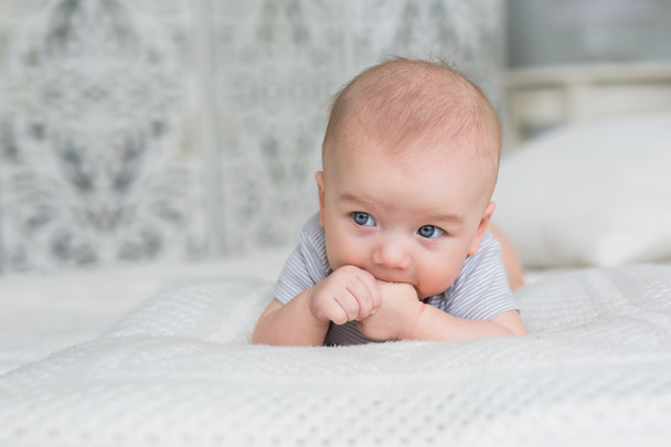 Lindo bebé se encuentra en una cama y chupar su dedo
 - Foto, imagen
