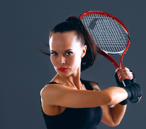 Woman playing tennis on gray background - Foto, afbeelding