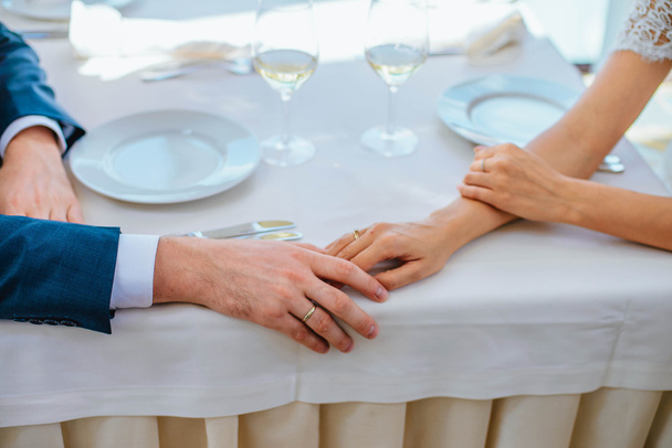 Braut und Bräutigam halten sich in einem Restaurant die Hand - Foto, Bild