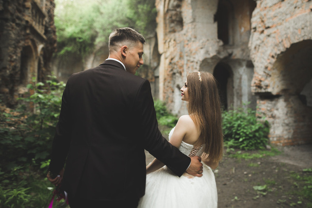 Beautiful fairytale newlywed couple hugging near old medieval castle - Photo, Image
