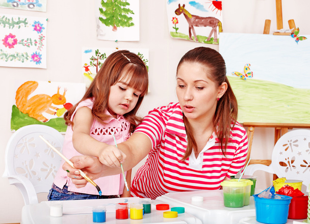 Child with teacher draw paints in play room. - Photo, Image