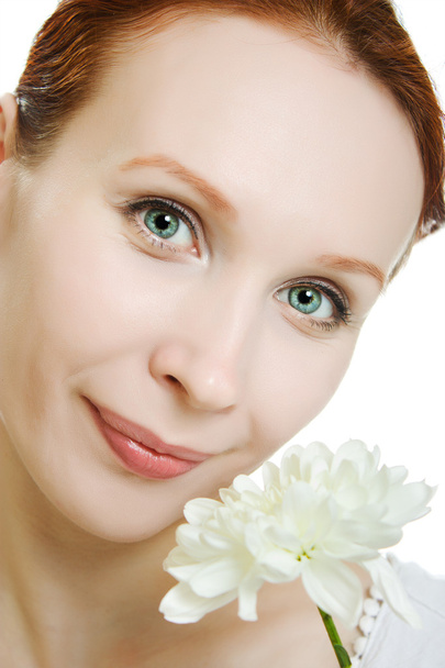 Healthy skin of young beautiful woman face with a flower in her hairs on a white background. - Фото, зображення