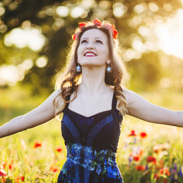 Beautiful young woman on the poppy field - Фото, изображение