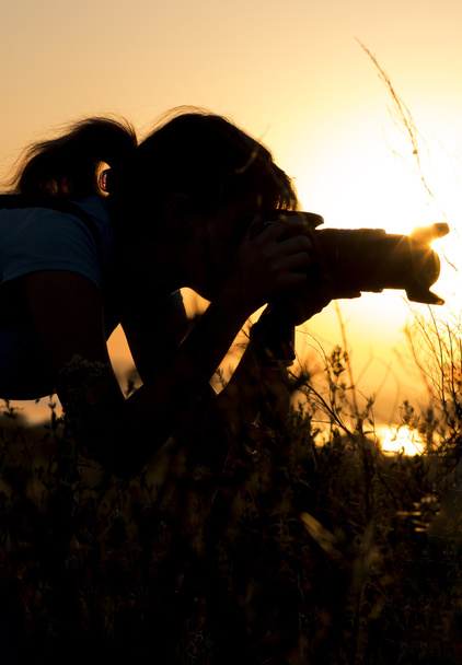 retrato de silueta de una mujer joven fotografiando una hermosa naturaleza al atardecer en equipo fotográfico
 - Foto, Imagen