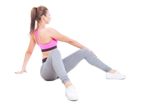 Fit girl sitting down twisting waist as training - Фото, изображение