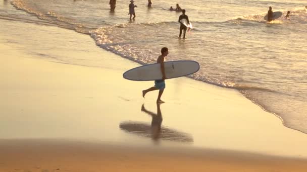 MOCIÓN LENTA: Feliz joven surfista corriendo con la tabla de surf en las manos en el océano
 - Imágenes, Vídeo