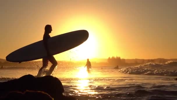 LOW MOTION: Adventurosa jovem surfista que corre para o oceano com prancha de surf
 - Filmagem, Vídeo