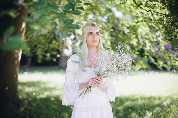 Panna Młoda z kwiatami, stojąc pod drzewem - Zdjęcie, obraz