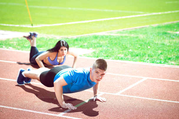 Young couple doing push ups on track. - Foto, Imagem
