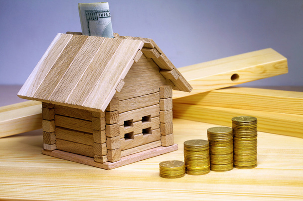Ένα μικρό σπίτι στέκεται σε δομικά υλικά και κέρματα. Πίστωση f - Φωτογραφία, εικόνα