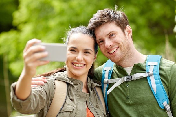 couple with backpacks taking selfie by smartphone - Fotó, kép