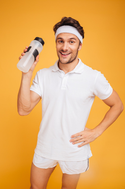 Portrait of a happy sports man holding bottle with water - Zdjęcie, obraz