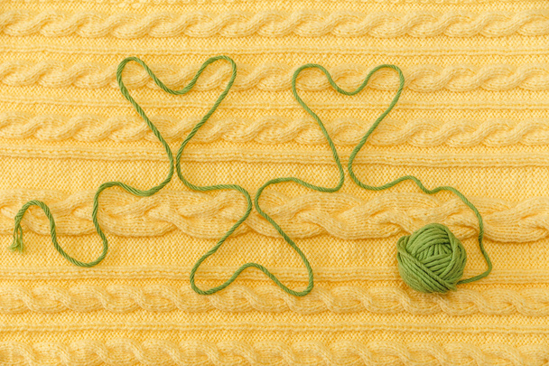 Yellow Knitted Background with Pattern and Braids; Green Ball.Fancywork.Hearts from Thread - Photo, Image