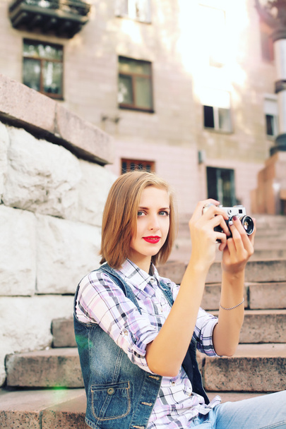 Portrait of young hipster girl making photo with vintage camera.  - 写真・画像
