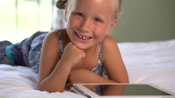 little cute girl plays a game on the tablet - Materiał filmowy, wideo