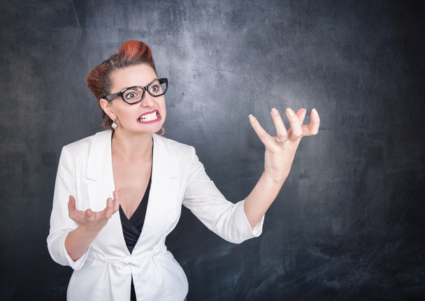 Angry teacher in glasses on blackboard background - Фото, изображение