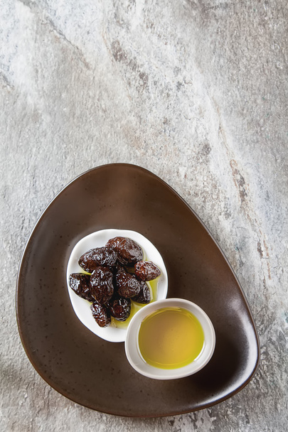 Green ripe olives and olive oil in a bowl. Dark background. Top  - 写真・画像